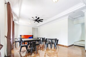 A dining area with a long table and chairs, a ceiling fan, and a tiled floor. - OYO 90480 Sultan Guest House (Malang)