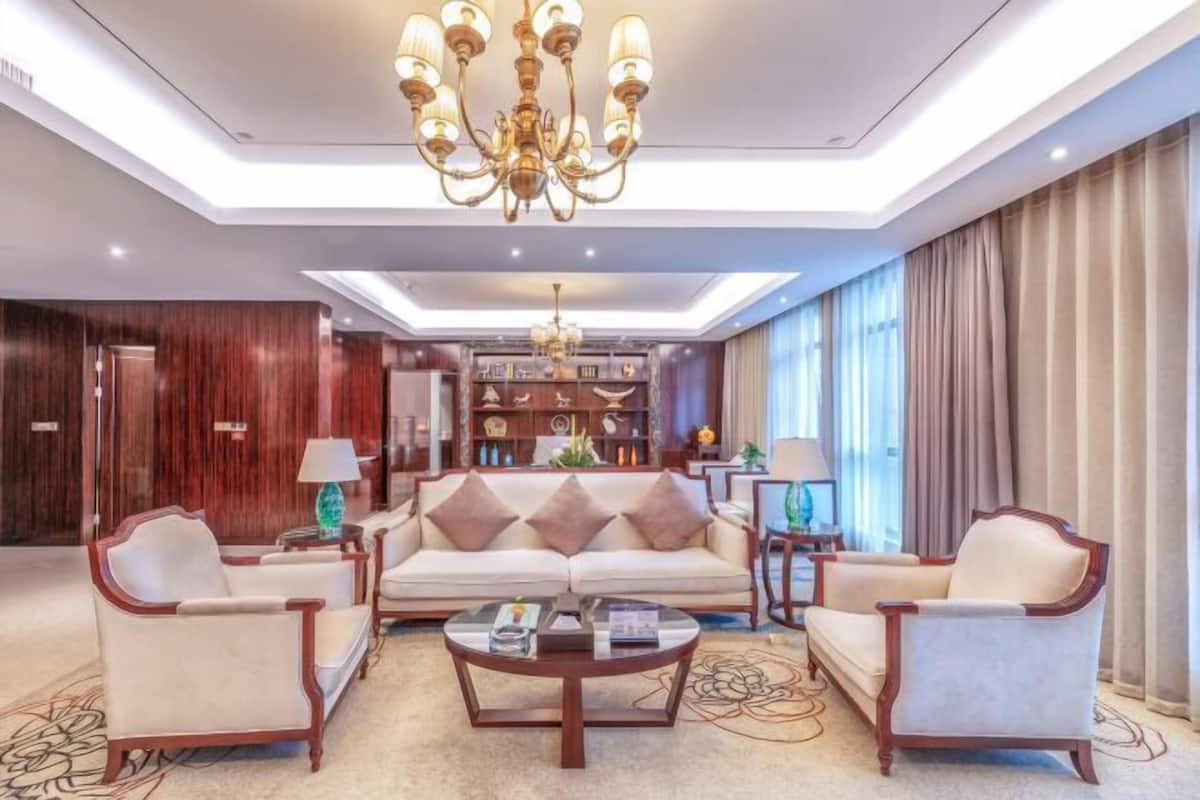 A spacious living room with a sofa set, armchairs, a coffee table, and a chandelier.