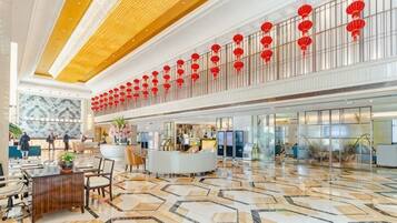 A spacious lobby with a high ceiling, a reception desk, and a patterned floor.