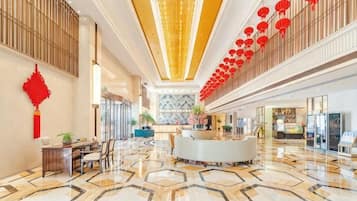 A spacious lobby with a reception desk, seating area, and a patterned floor.