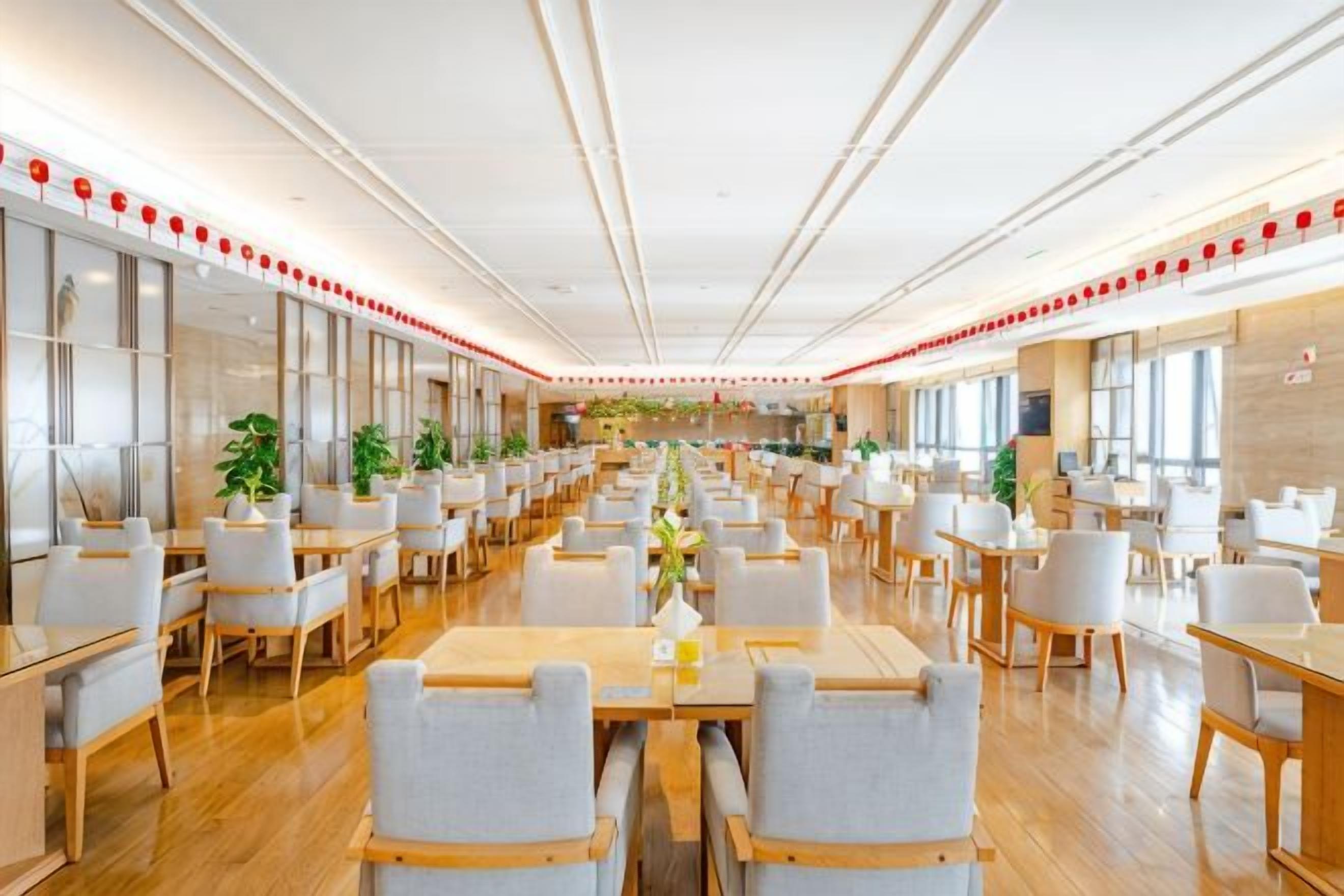 Un comedor amplio con múltiples mesas y sillas, ventanas grandes y un diseño de interiores moderno.