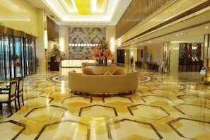 A hotel lobby with a central seating area, a reception desk, and a marble wall. - Ruili Bund Hotel (Rui'an)