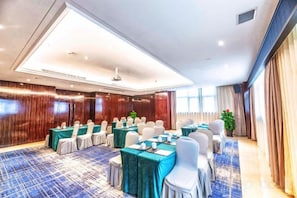 Una sala de conferencias con mesas redondas, sillas y alfombra azul.