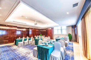 Una sala de conferencias con mesas redondas, sillas y alfombra azul.