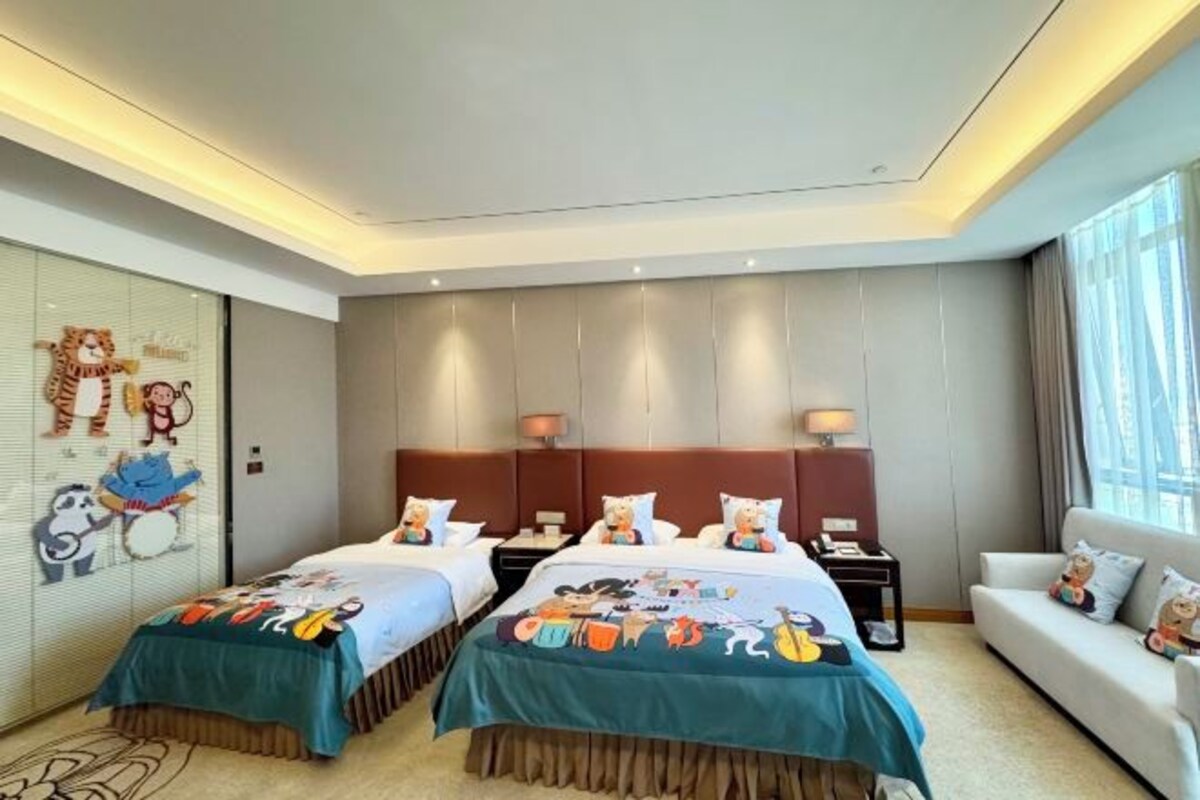 Een hotelkamer met twee bedden, een bank en een groot raam.