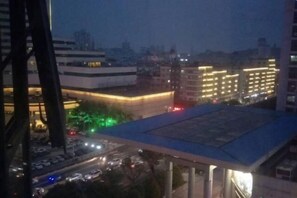 A cityscape at dusk with illuminated buildings and a parking area. - Ruili Bund Hotel (Rui'an)