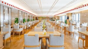 A spacious dining area with multiple tables and chairs, large windows, and a modern interior design.