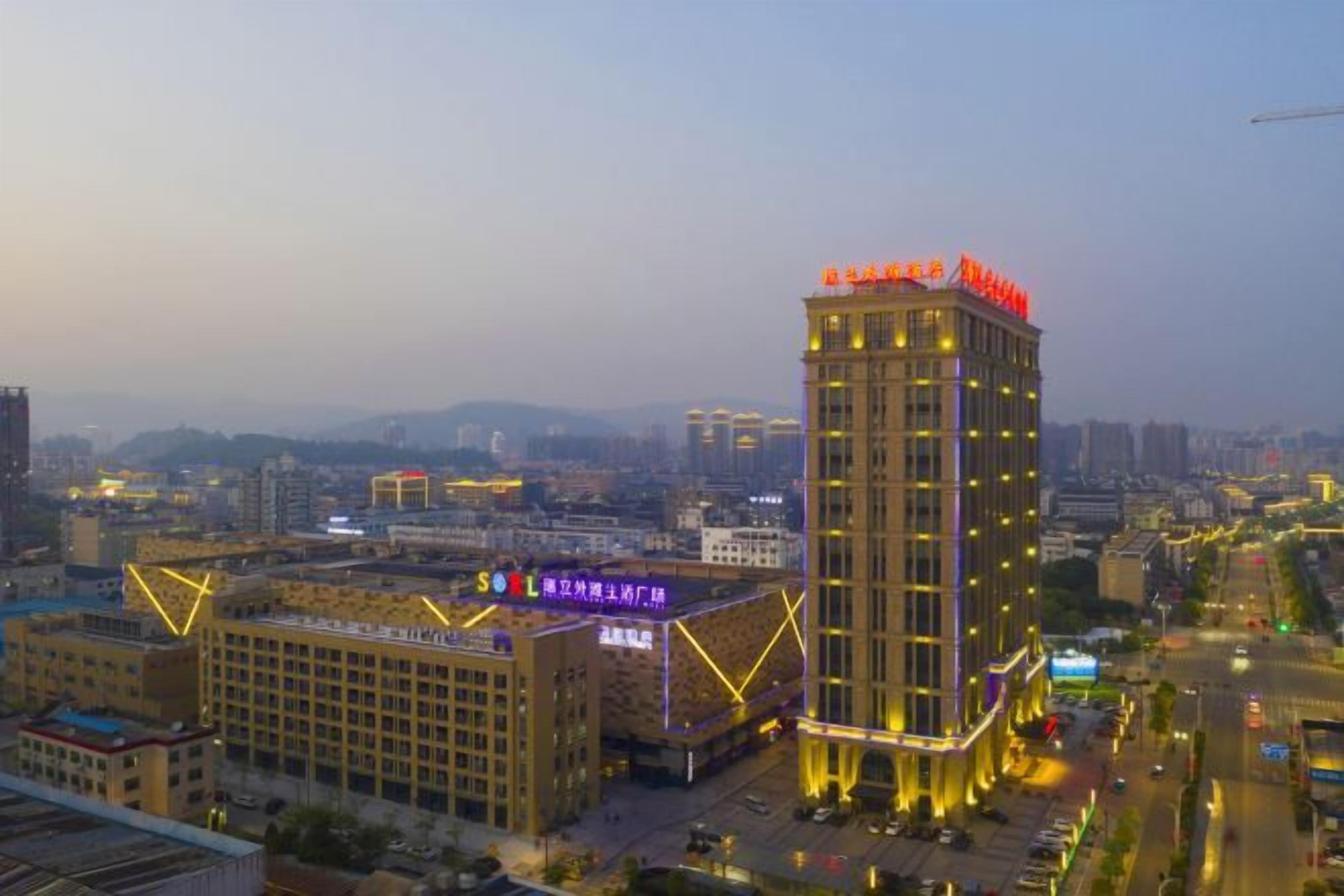 A high-rise building with illuminated signage, surrounded by other buildings and a cityscape.