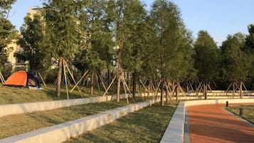 A park with a tent, trees, and a paved walkway.