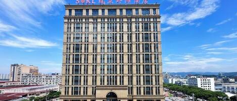 Un hôtel à plusieurs étages, doté d’une entrée imposante et offrant une vue dégagée sur le paysage urbain environnant.