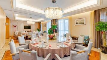 A dining area with a round table set for six, surrounded by chairs, in a well-lit room with a chandelier.