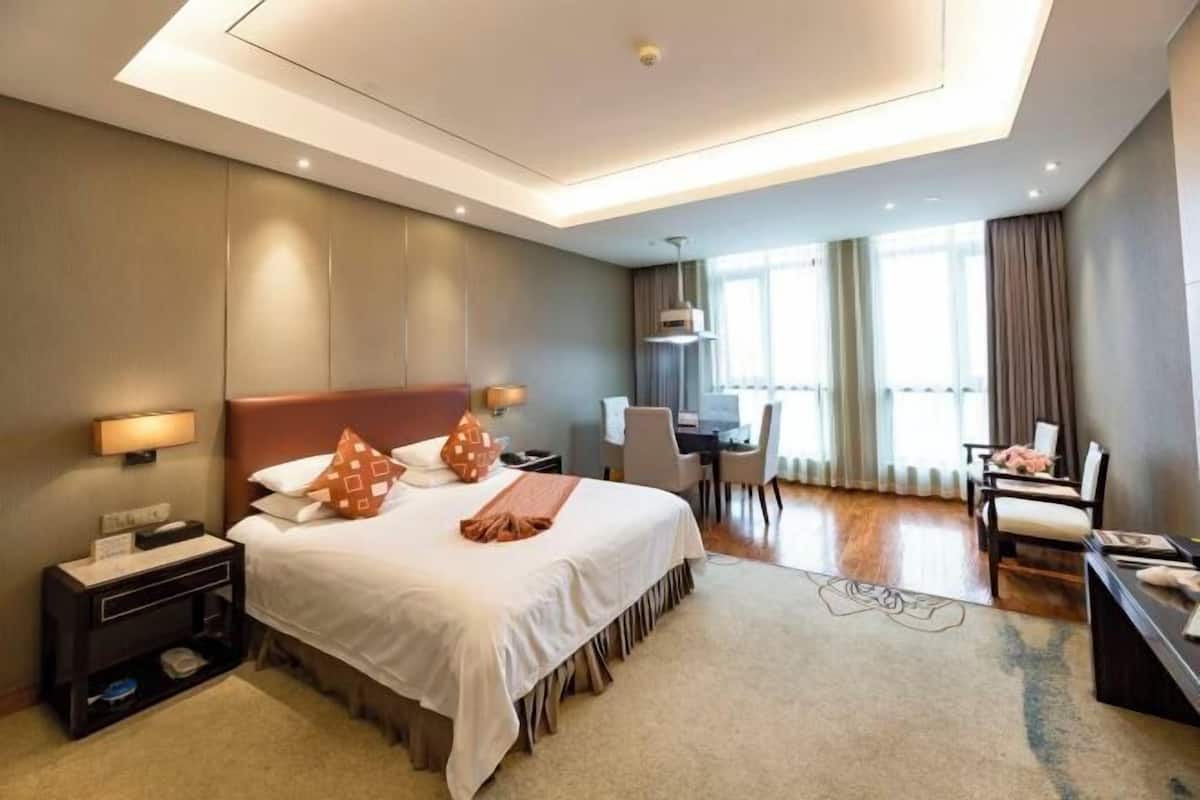 A hotel room with a bed, bedside tables, a desk, and a chair.