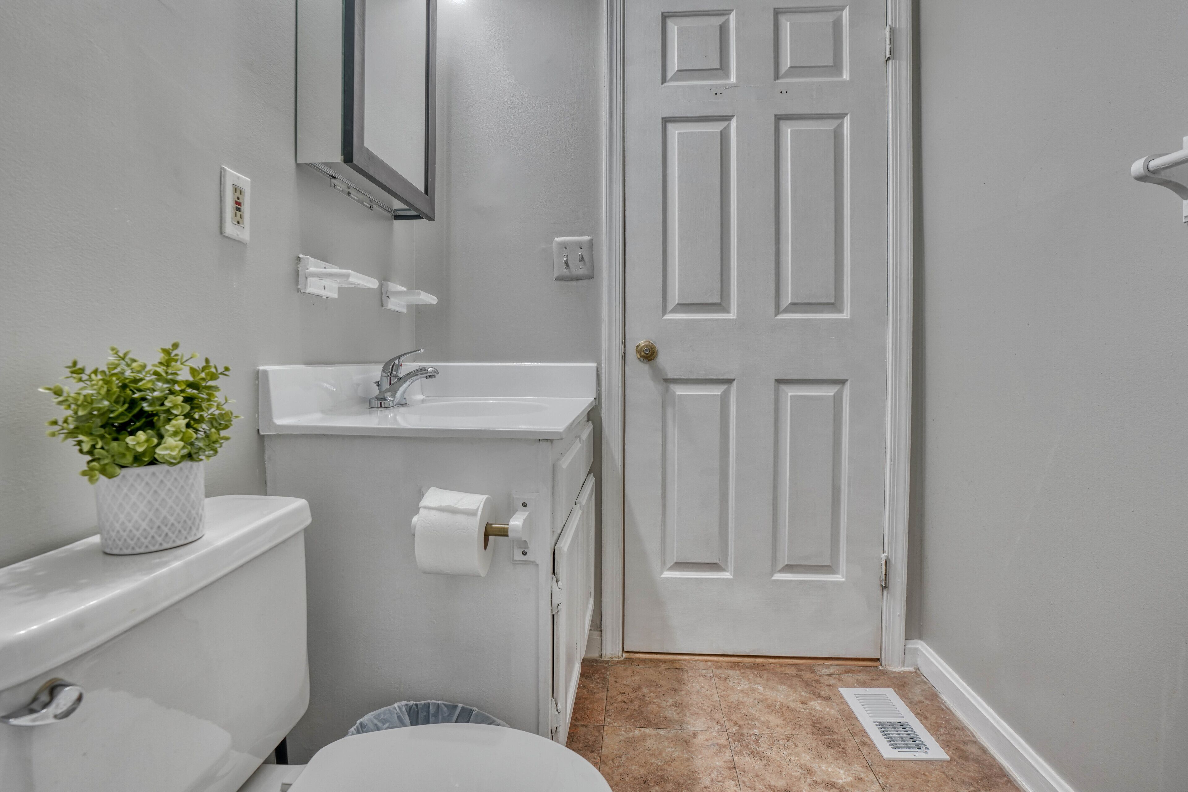 Een badkamer met toilet, wastafel en spiegel.