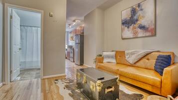 A living room with a leather sofa, a vintage trunk, and a modern abstract painting.