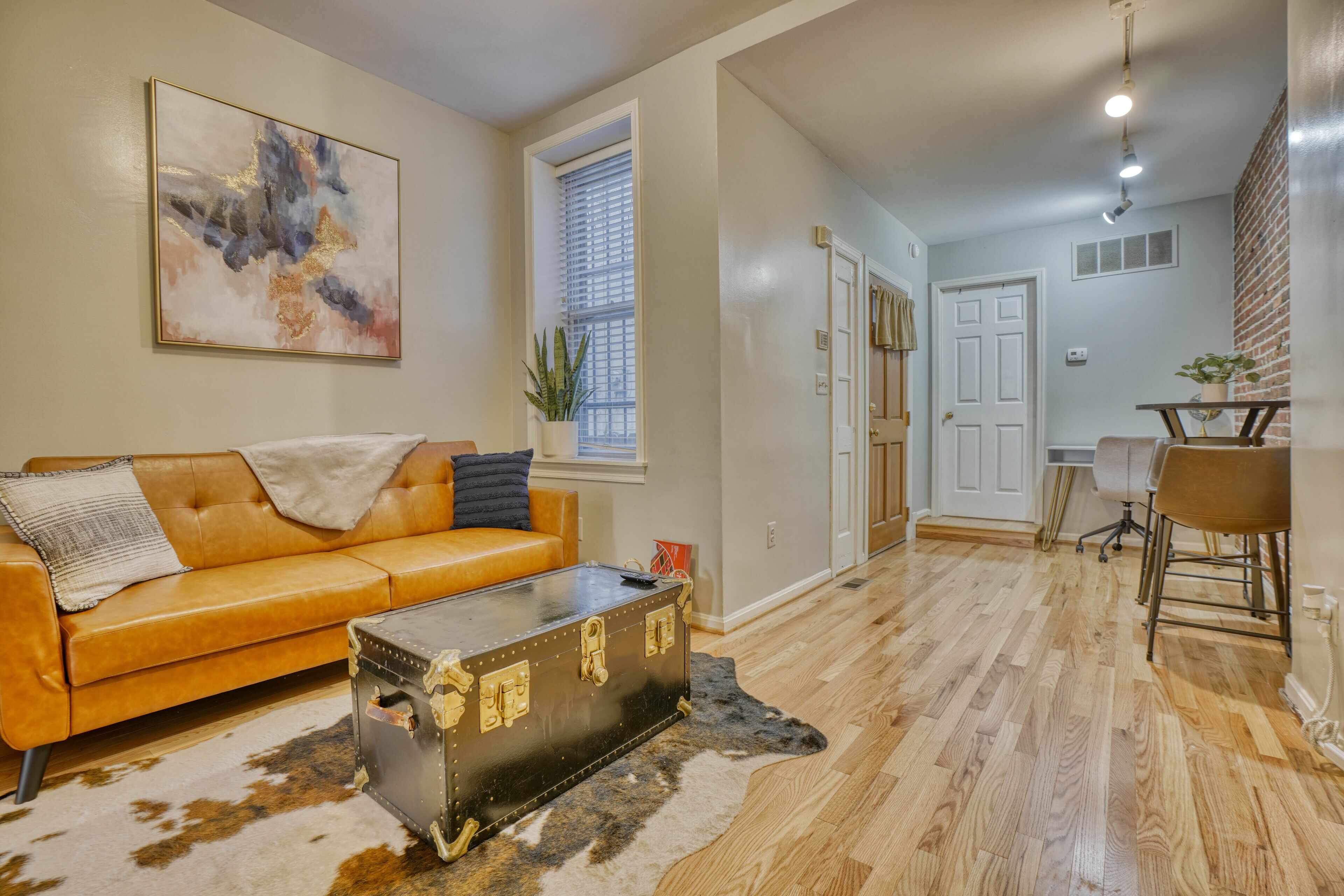 A living room with a leather sofa, a vintage suitcase, and a cowhide rug.