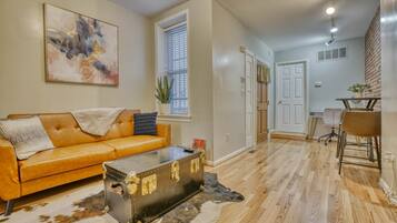 A living room with a leather sofa, a vintage suitcase, and a cowhide rug.