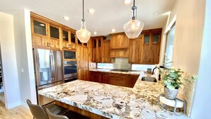 A modern kitchen with wooden cabinets, stainless steel appliances, and a marble countertop.