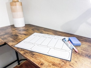 A wooden table with a planner, pens, and a blue notebook.
