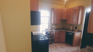 A kitchen with wooden cabinets, a black refrigerator, and a granite countertop. - Eastbayside/Munjoy - Charming Downtown Escape (Portland)