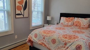 A bedroom with a bed, two windows, a ceiling fan, and a wall-mounted lamp. - Eastbayside/Munjoy - Charming Downtown Escape (Portland)
