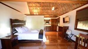 Un dormitorio con suelo de madera, una cama, mesitas de noche y un televisor en la pared.