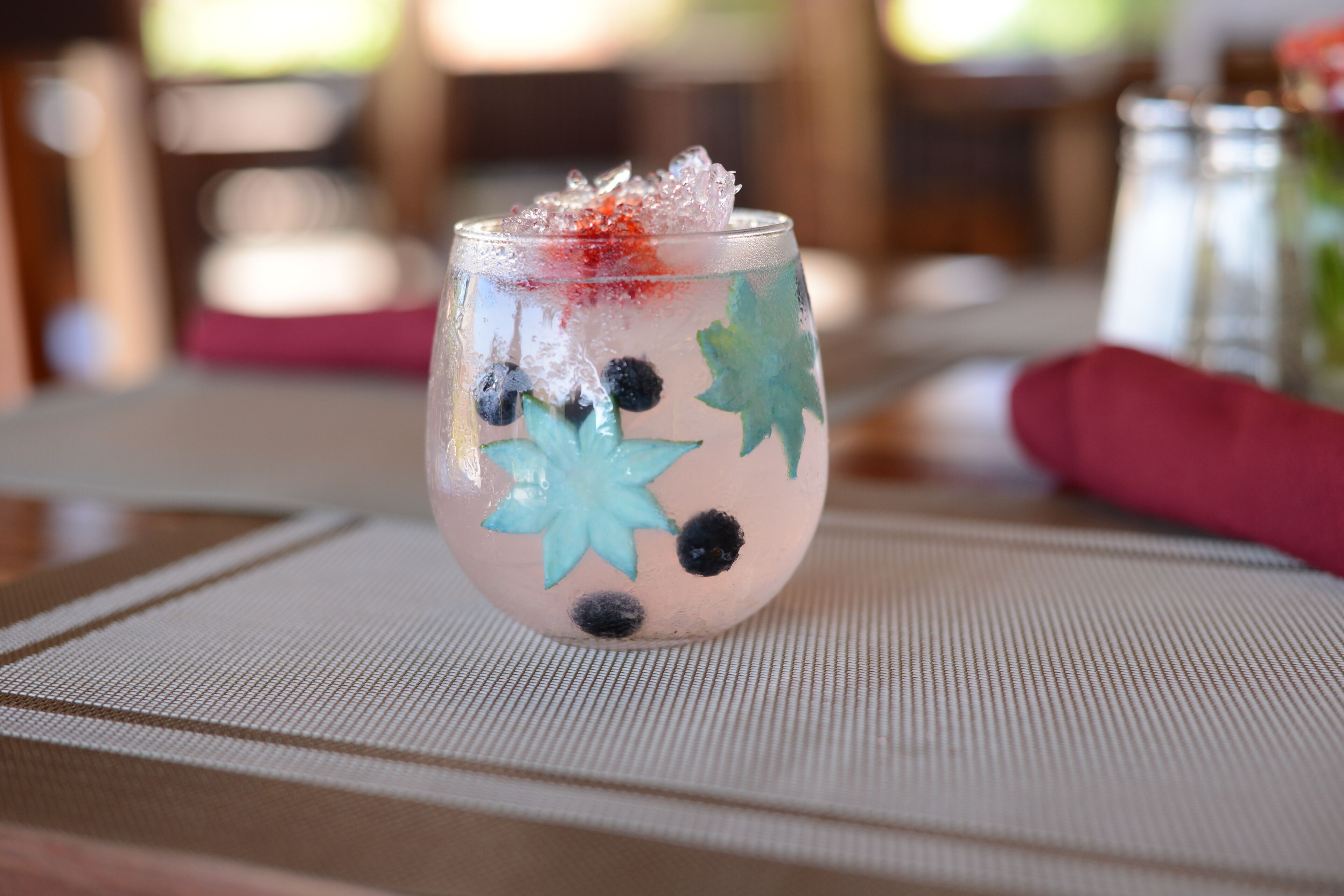Un vaso con diseño decorativo y cubitos de hielo sobre un mantel texturizado.