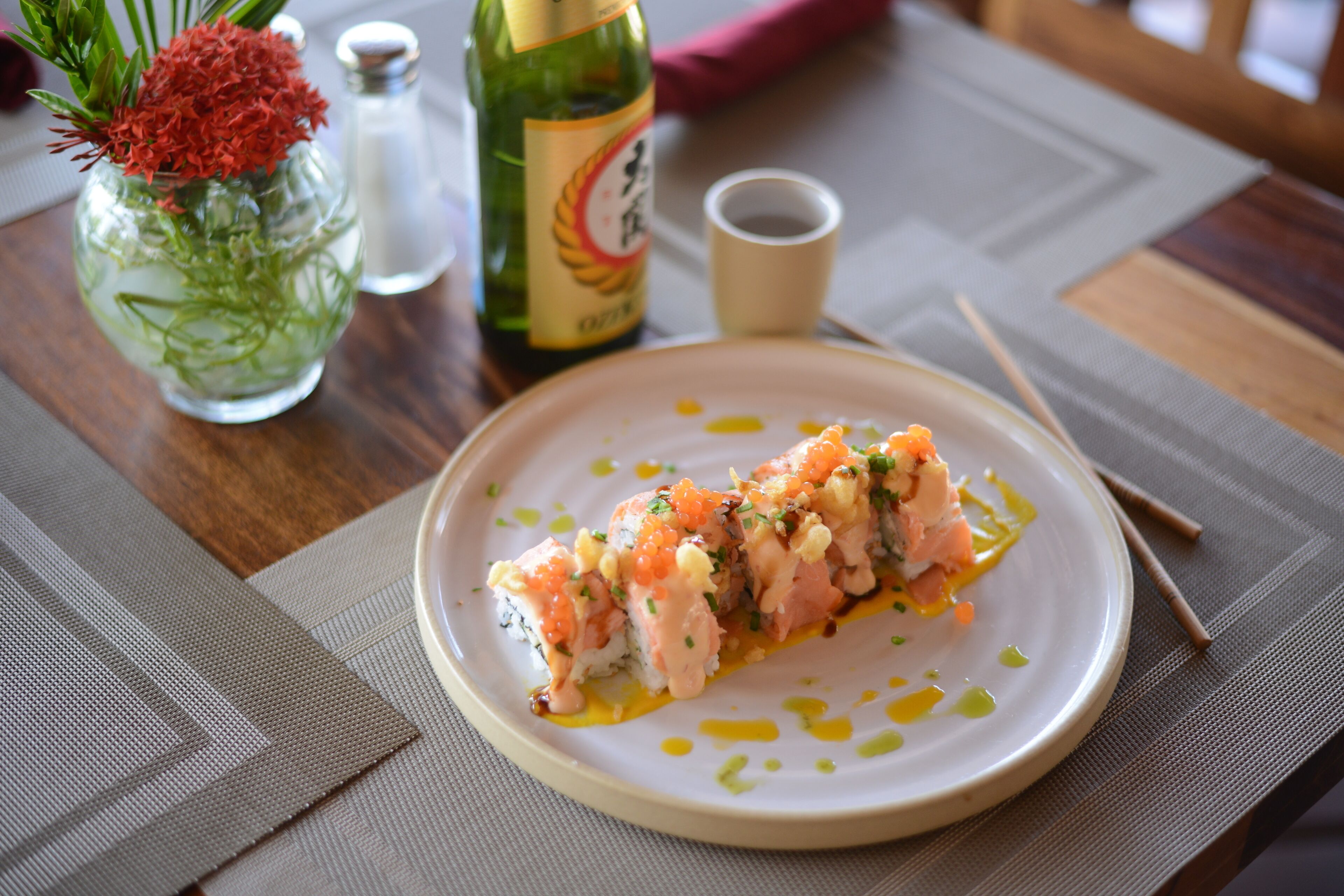 A plate of sushi with a bottle of sake and a salt shaker on a table.