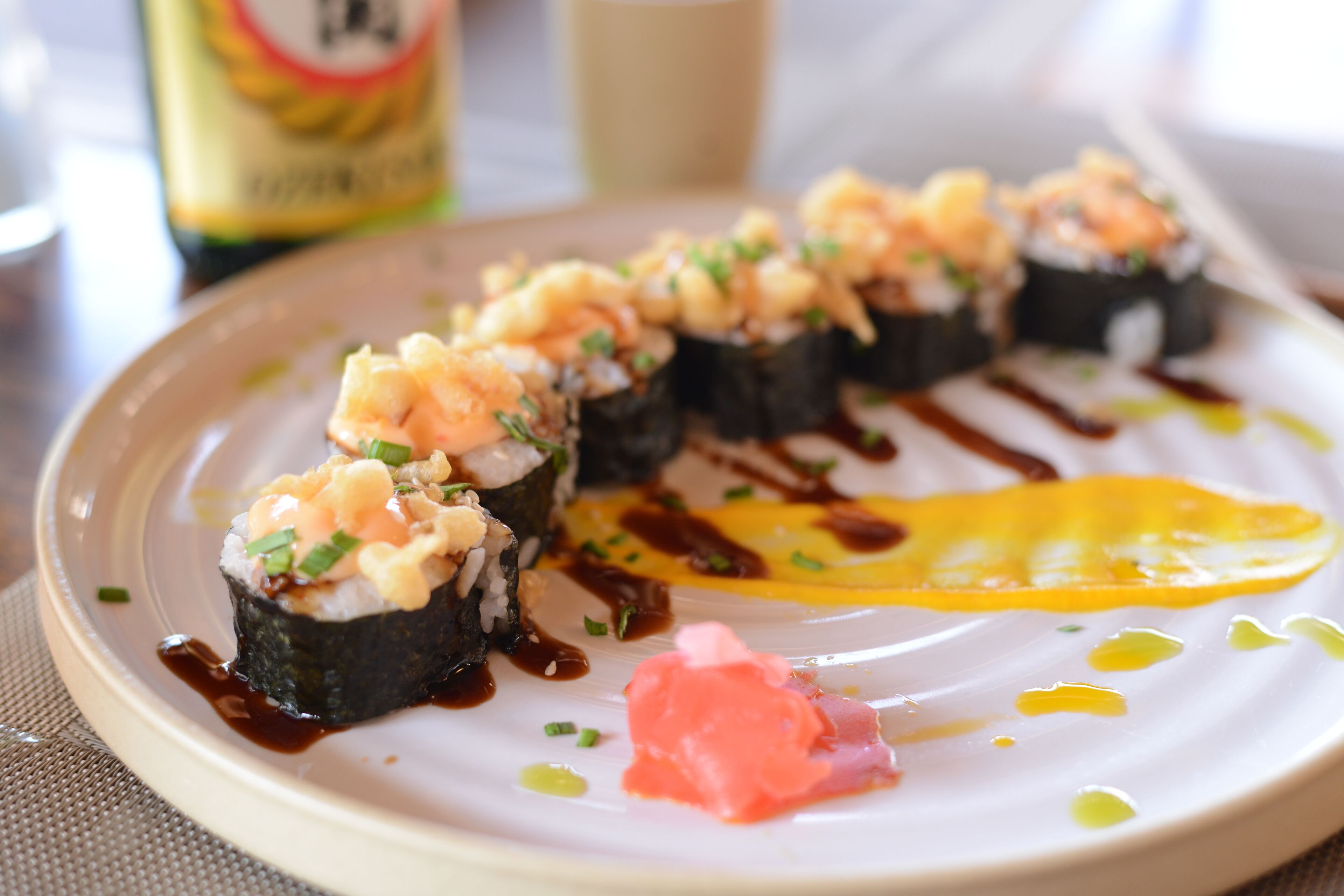Een bord sushi met een sausdruppel en een plak ei.