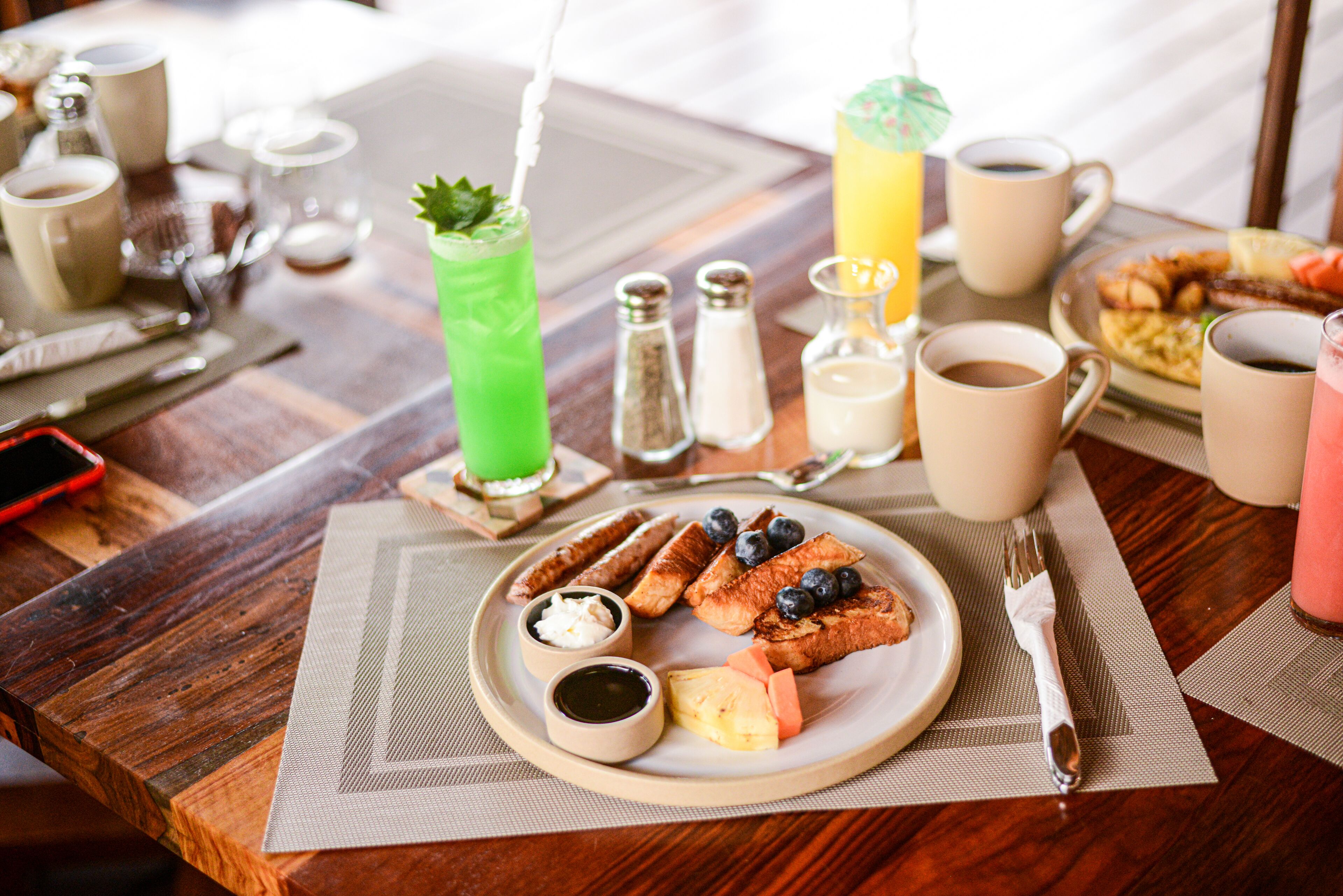 Un desayuno con un plato de comida, bebidas y salsas sobre una mesa de madera.