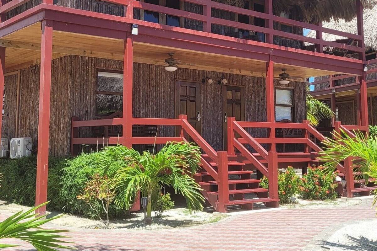 Un edificio de dos pisos con techo de paja y balcones de madera rojos.