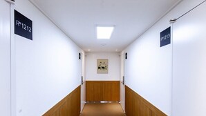 A hallway with wooden paneling and carpet, flanked by white walls with room number signs RM1212 and RM1213. - Step Inn Myeongdong 2 (Seoul)