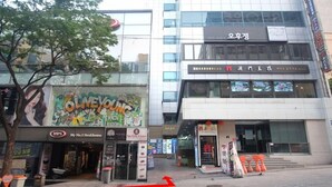 A street view with a restaurant named 'OLNEYONG' and a building with signage in a foreign language. - Step Inn Myeongdong 2 (Seoul)