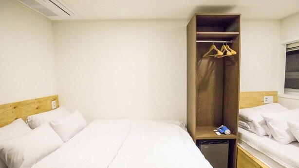 Une chambre d’hôtel avec un grand lit, une armoire en bois et une petite table de chevet.