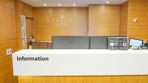 A reception desk with a 'information' sign, a Samsung monitor, and a bulletin board with notices. - Step Inn Myeongdong 2 (Seoul)