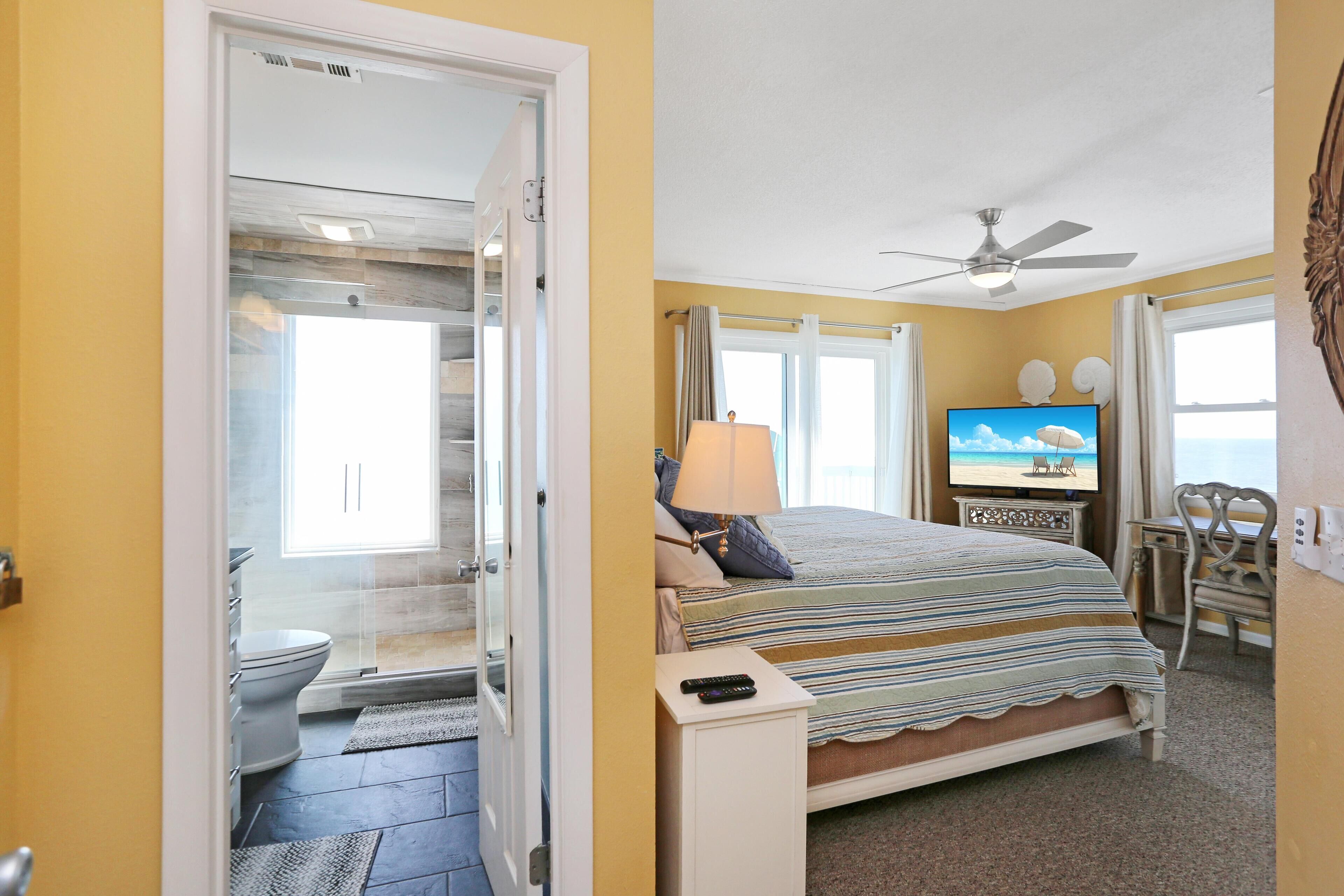 A hotel room with a bed, a television, a desk, and a bathroom with a shower.