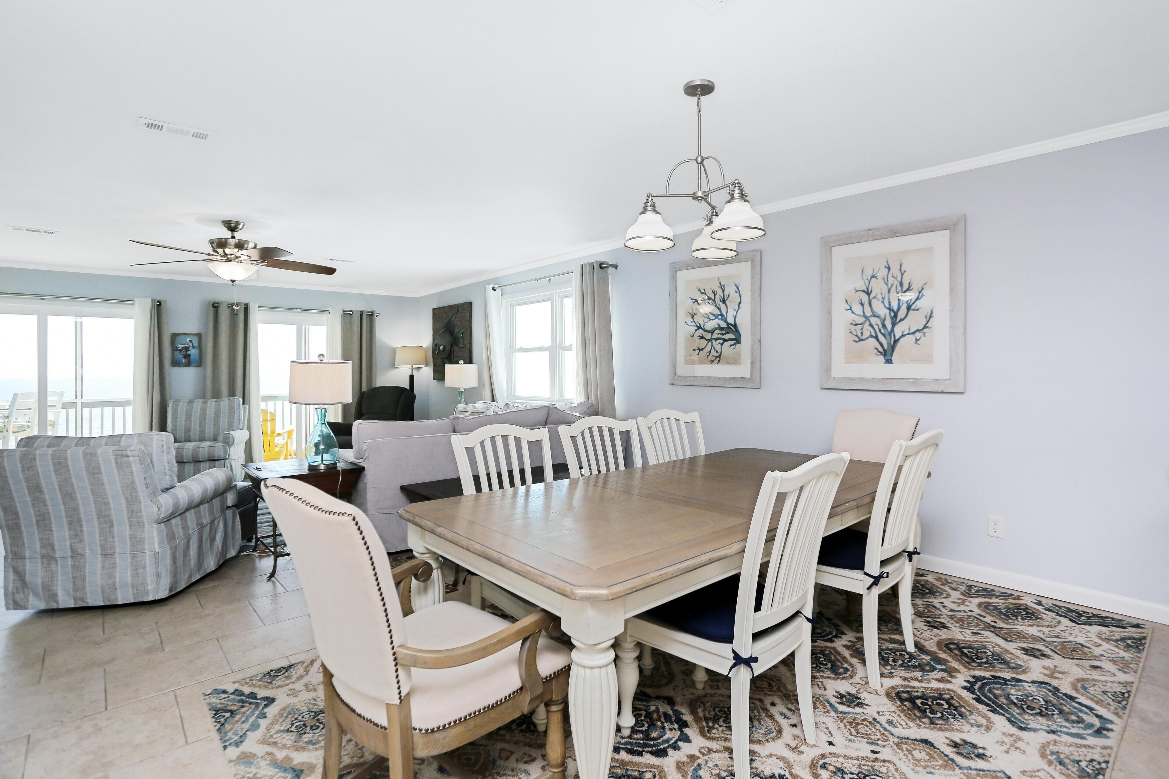 A dining area with a wooden table and white chairs, a ceiling fan, and two wall-mounted light fixtures.