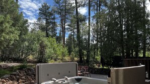 Ein Whirlpool mit Steinfassade, umgeben von einem Garten mit verschiedenen Pflanzen und einer Holzterrasse.