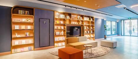 A modern library with bookshelves, a television, and seating areas.