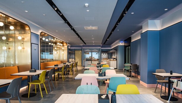 A modern restaurant interior with multiple seating areas, a bar, and a view of the cityscape. - Hanting Beijing Sanyuanqiao Yansha Embassy Hotel (Beijing)