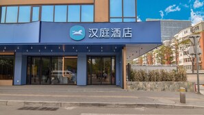 A hotel with a blue facade, large glass entrance, and a sign with a horse logo. - Hanting Beijing Sanyuanqiao Yansha Embassy Hotel (Beijing)