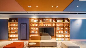 A modern library with bookshelves, seating, and a television. - Hanting Beijing Sanyuanqiao Yansha Embassy Hotel (Beijing)