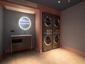 Une salle de bain moderne avec un meuble-lavabo, un miroir rond et quatre machines à laver fixées au mur.