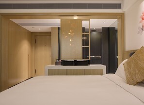 Une chambre d’hôtel moderne avec un grand lit, une coiffeuse intégrée avec un miroir et une armoire.