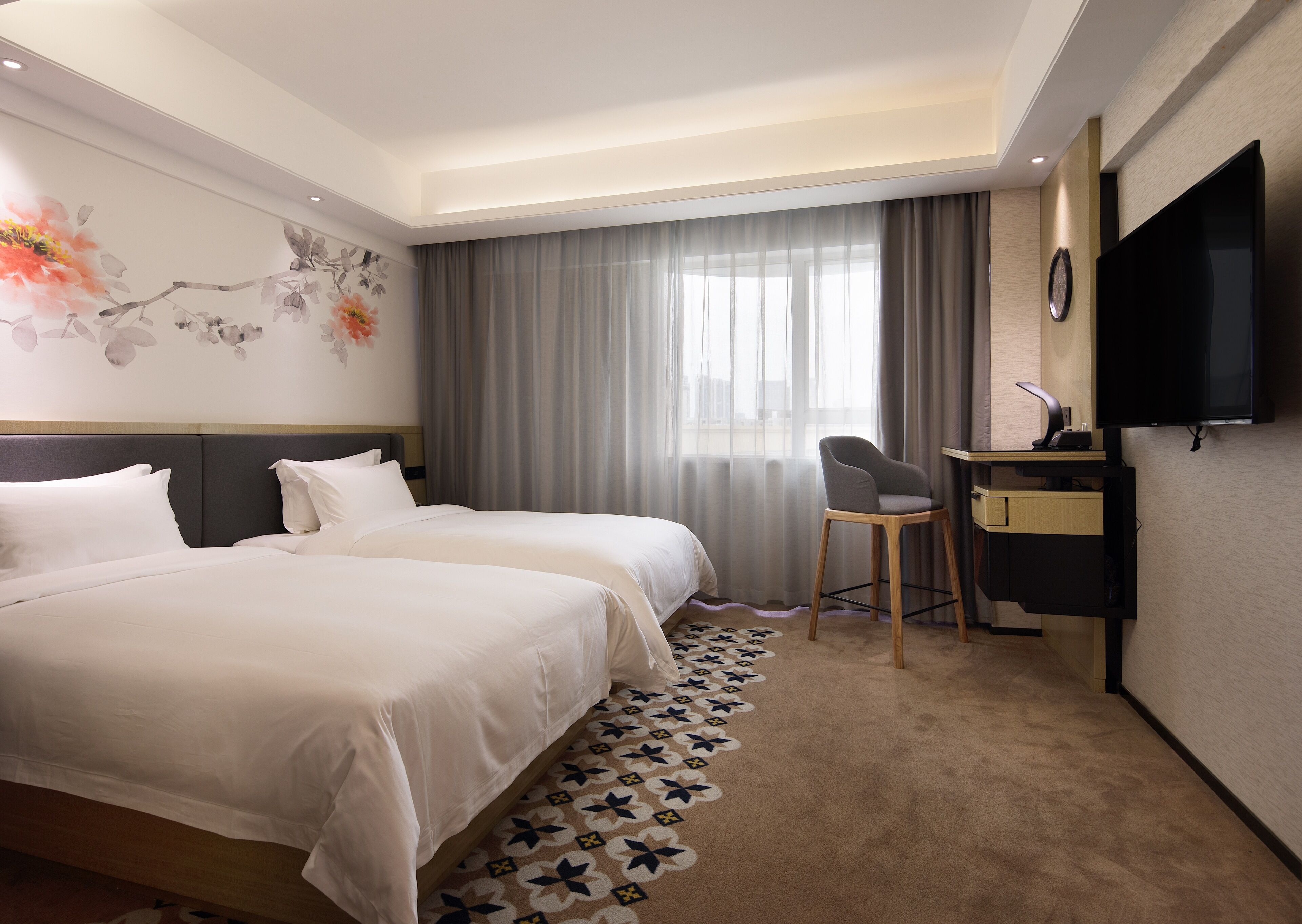 A hotel room with two beds, a desk, a chair, a television, and a large window with curtains.