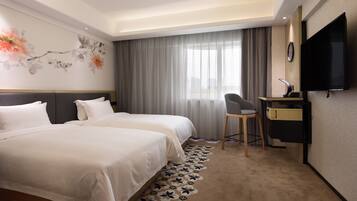 A hotel room with two beds, a desk, a chair, a television, and a large window with curtains.