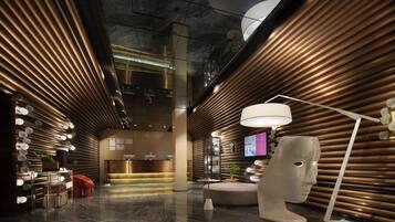 A modern lobby with a reception desk, seating area, and a large wall-mounted television.