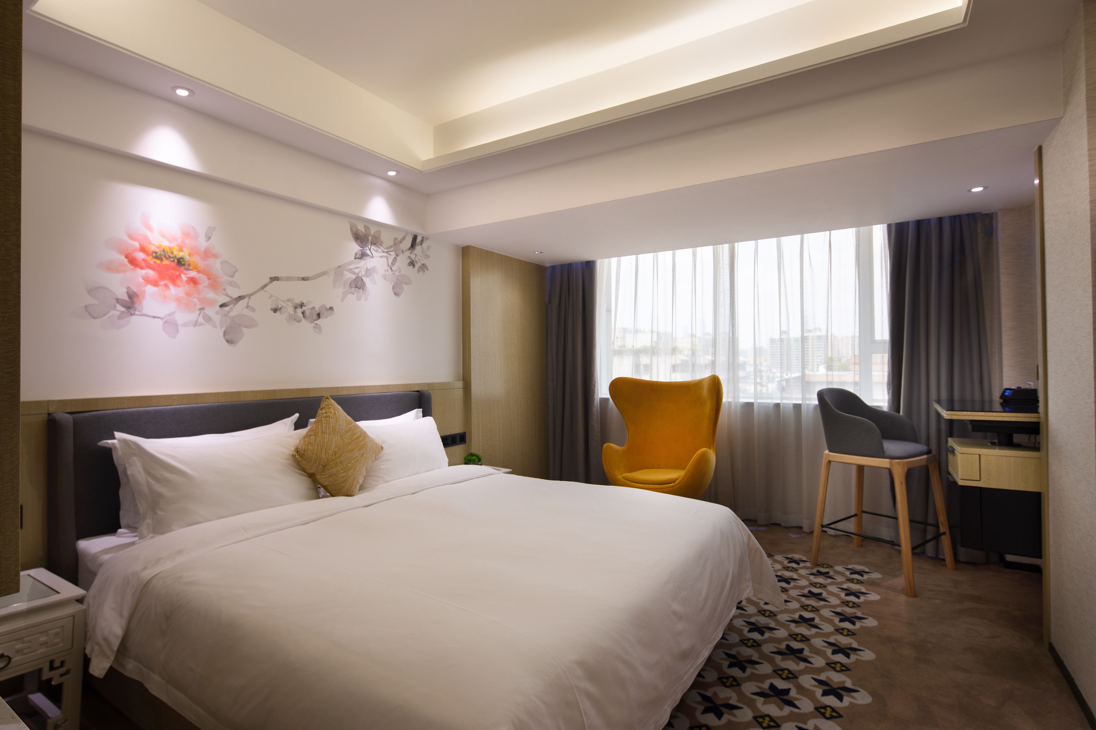 Une chambre d’hôtel avec un grand lit, un bureau, une chaise et une fenêtre avec des rideaux.