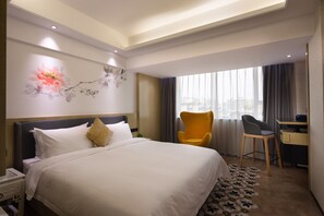 Une chambre d’hôtel avec un grand lit, un bureau, une chaise et une fenêtre avec des rideaux.