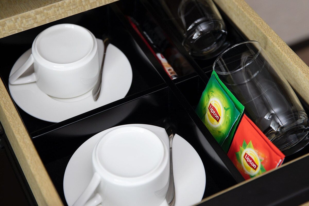 Eine Schublade mit weißen Tassen, Untertassen, einem Glas und Lipton Teebeuteln.