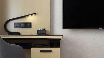 A modern office space with a desk, chair, lamp, and a mounted flat-screen TV.